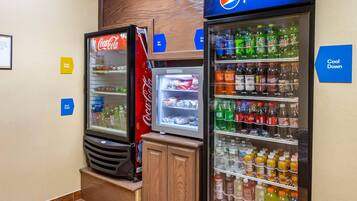 A vending area with Coca-Cola and Pepsi refrigerators, ice dispensers, and a sign indicating 'Cool Down' and 'Ice Box'.