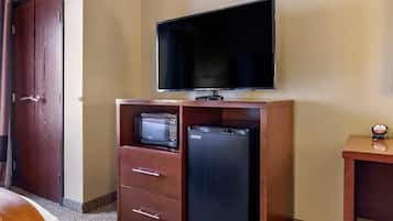 Habitación de hotel con un armario de madera que contiene un microondas, un refrigerador y un televisor de pantalla plana.