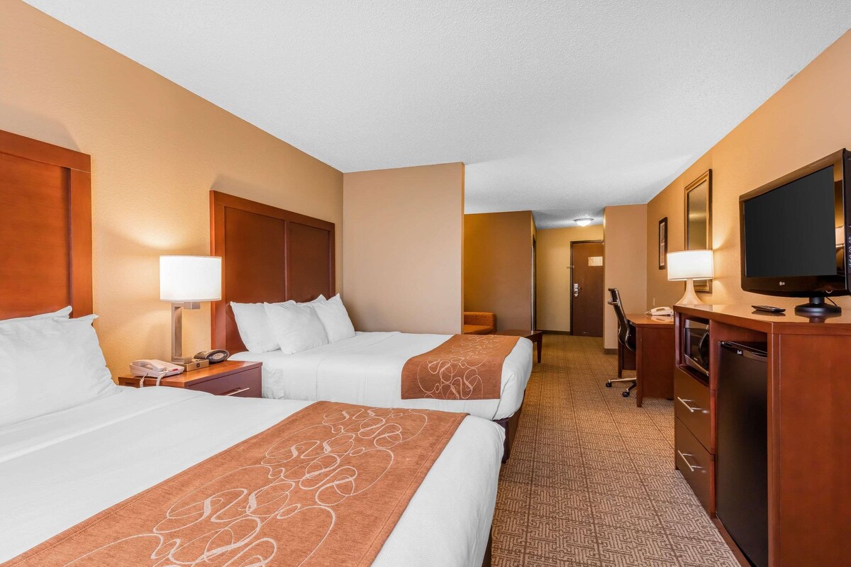 A hotel room with two beds, a desk, a television, and a minibar.