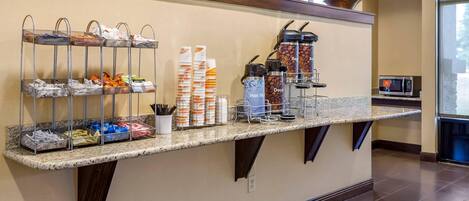 A reception area with a self-service beverage station, a microwave, and a potted plant.