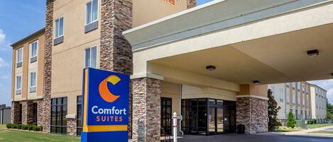 A Comfort Suites hotel with a stone facade, a blue sign, and a covered entrance.