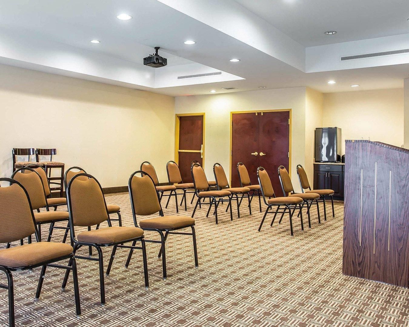 A conference room with rows of chairs, a podium, and a television.