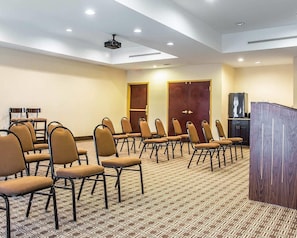 Un salón de conferencias con filas de sillas, un atril y una televisión.