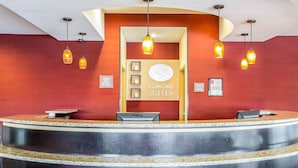 Un espace d’accueil doté d’un comptoir de réception incurvé, d’un éclairage suspendu et d’une enseigne indiquant « Comfort Suites ».