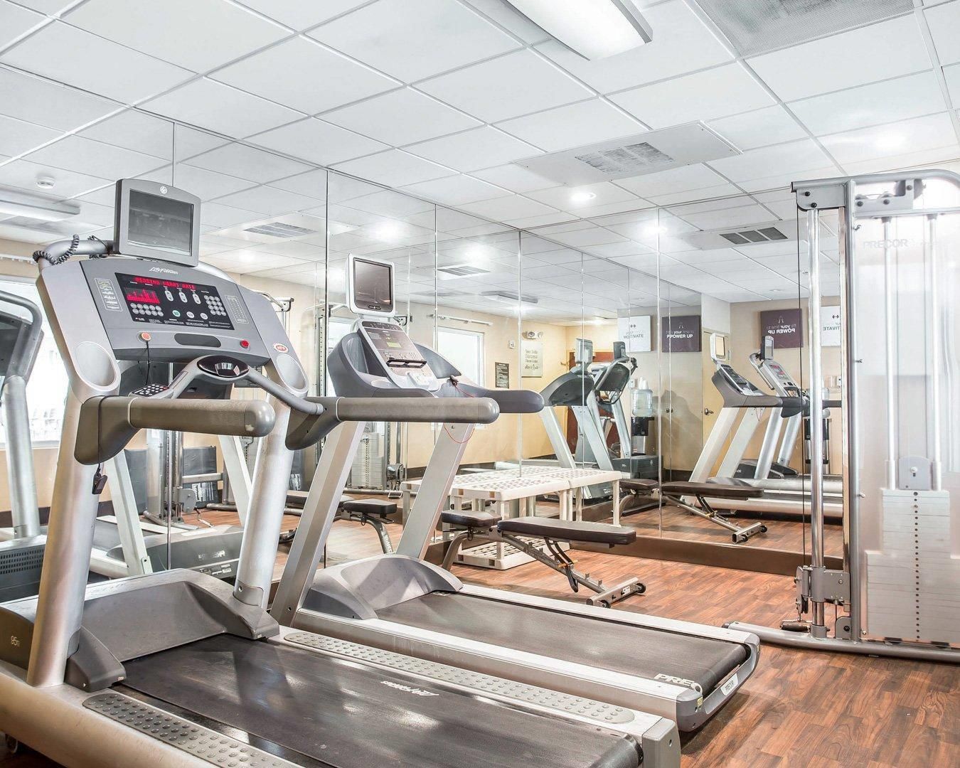 A gym with treadmills, exercise equipment, and mirrors on the walls.