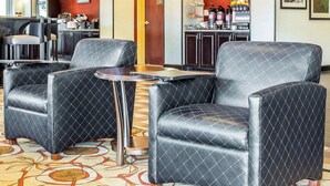 Un hall d’hôtel avec des fauteuils en cuir, une petite table ronde, un coin café et, au fond, un espace cuisine.