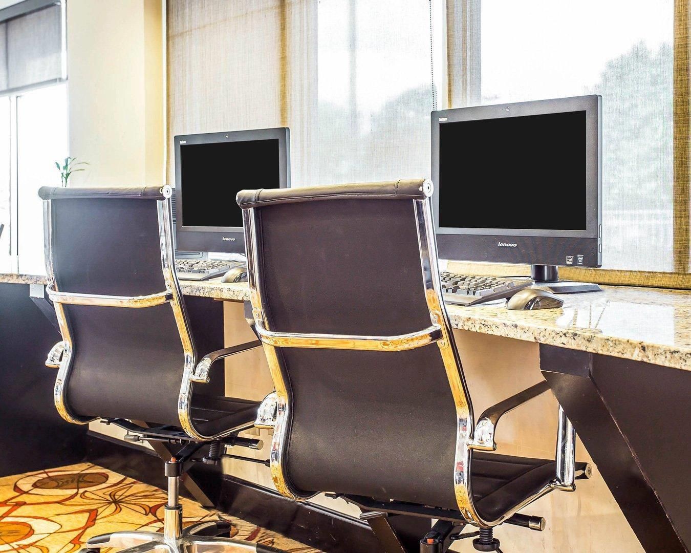 Drie bureaustoelen met bevestigde monitoren, een toetsenbord en een muis op een bureau.