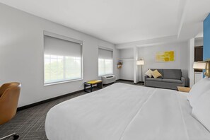 Een hotelkamer met een groot bed, een slaapbank, een stoel en een bijzettafeltje.
