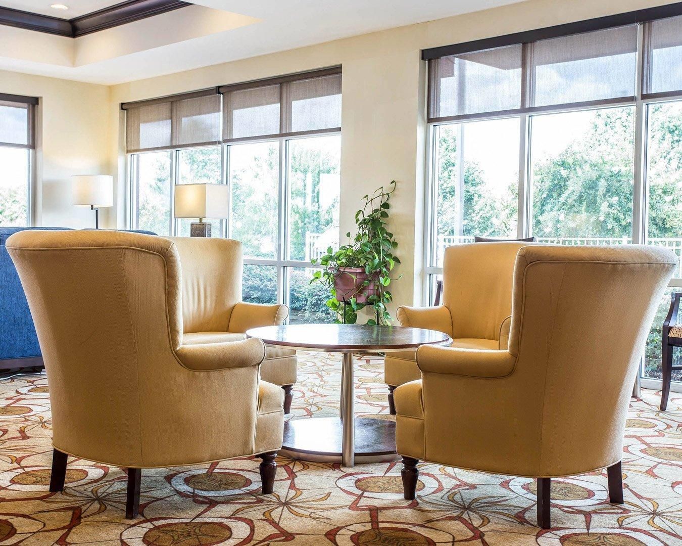 A room with two armchairs, a round table, and a potted plant.