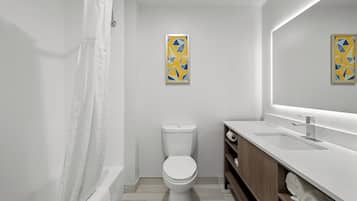 A modern bathroom with a toilet, a shower with a white curtain, and two framed wall art pieces.