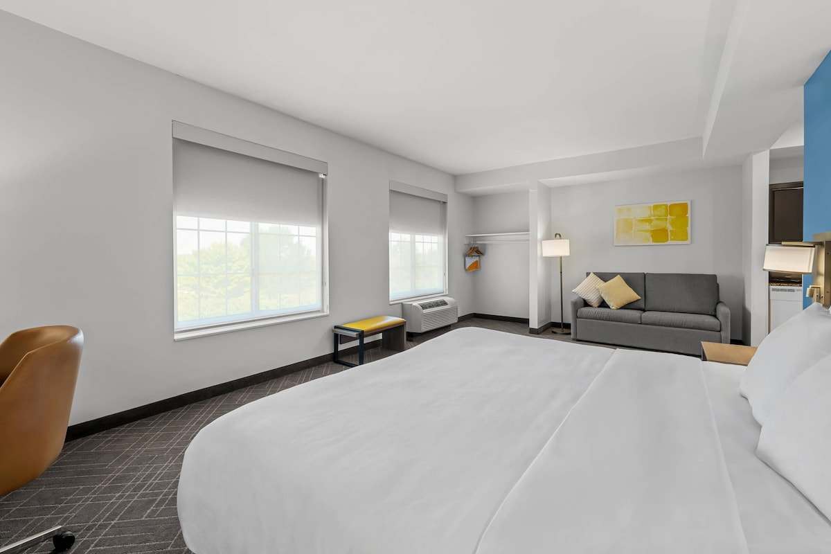 Een hotelkamer met een groot bed, een bank, een stoel, een kleine tafel en een raam.