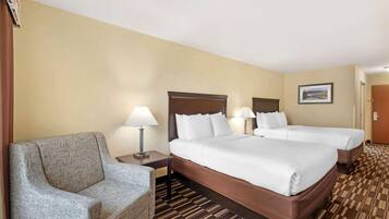 A hotel room with two beds, a sofa, and a nightstand with lamps.