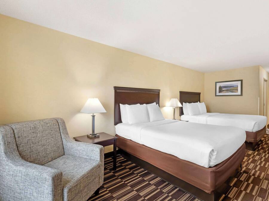 A hotel room with two beds, a sofa, and a nightstand with lamps.