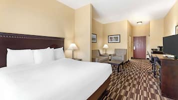 Une chambre d’hôtel avec un grand lit, deux fauteuils, un bureau et un téléviseur.