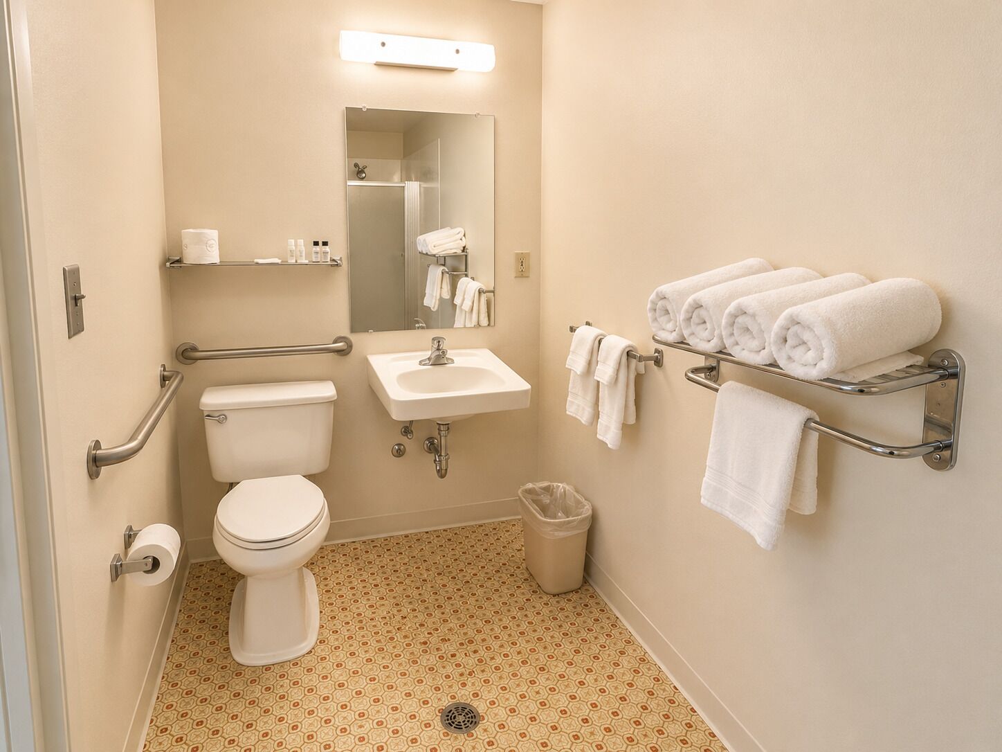 Un baño con inodoro, lavamanos, espejo, toallero y barras de apoyo.