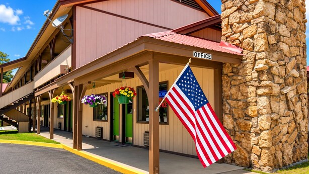 A building with a stone wall, an American flag, and hanging flower baskets.
