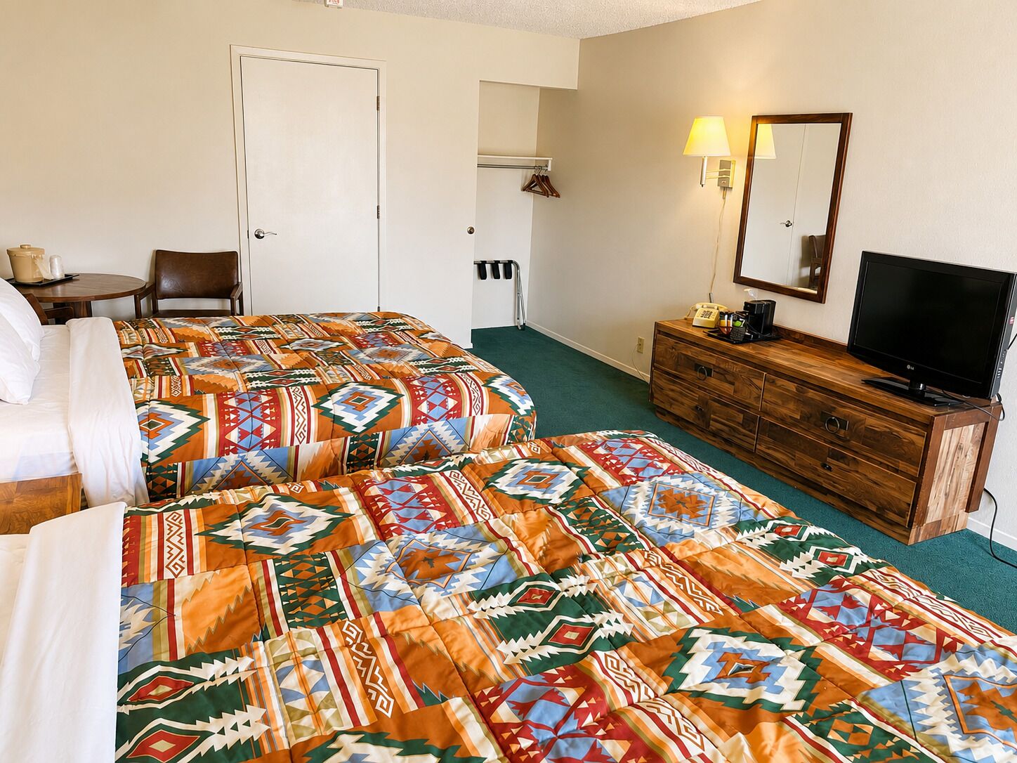 A hotel room with two beds, a wooden dresser, a television, and a chair.