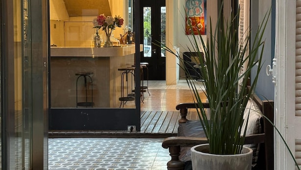 An open-plan living area with a tiled floor, a large potted plant, and a hanging light fixture. - Hotel Costa Rica (Buenos Aires)