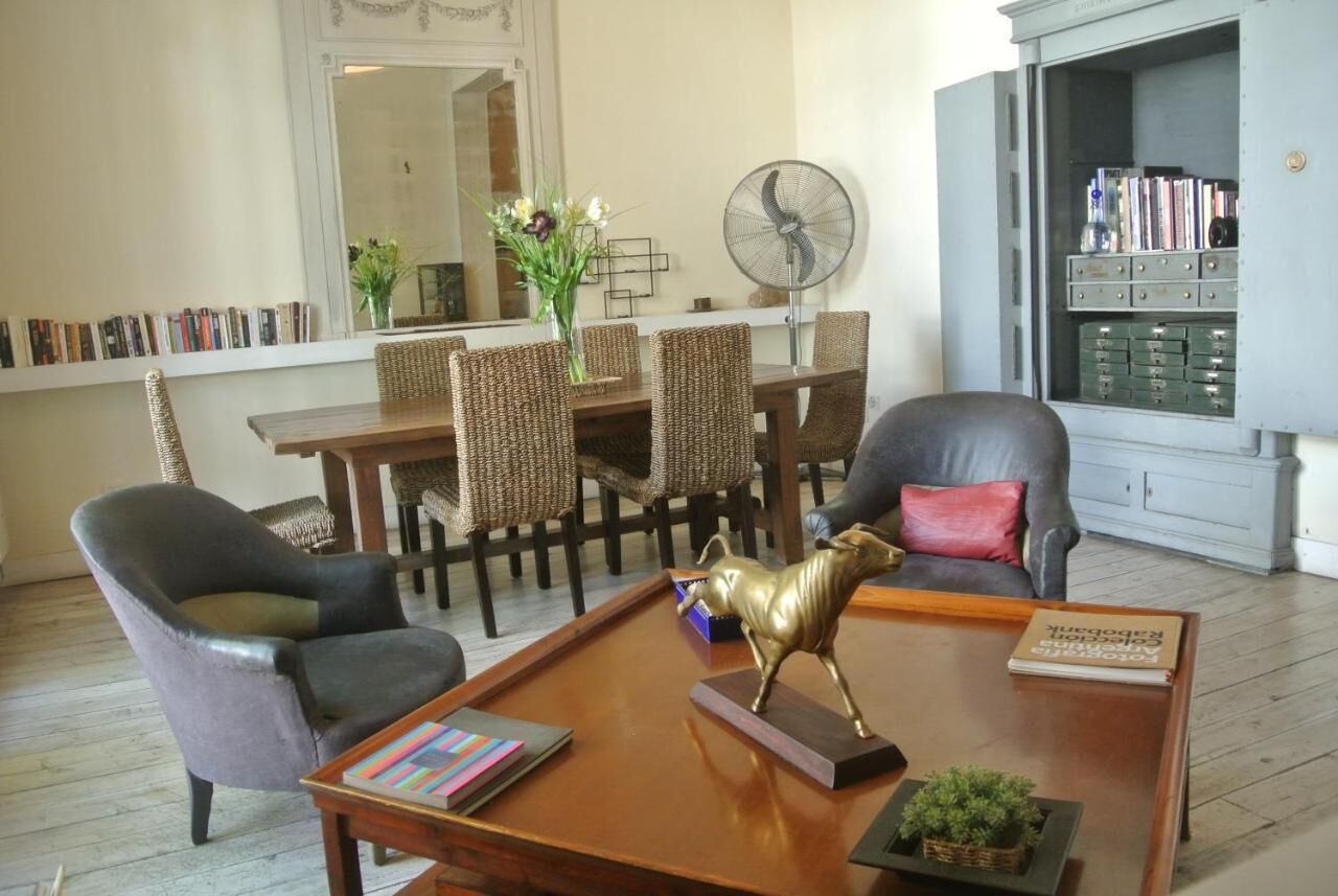 Un salón con una mesa de comedor, sillas, una mesa de centro con una figurita de caballo decorativa, una estantería y un aparador con cajones.