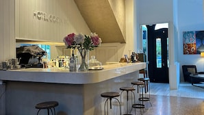 A modern hotel bar with a high ceiling, a chandelier, and a bar counter with stools. - Hotel Costa Rica (Buenos Aires)