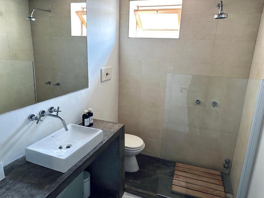 Une salle de bain avec un grand lavabo, un miroir et un espace douche.