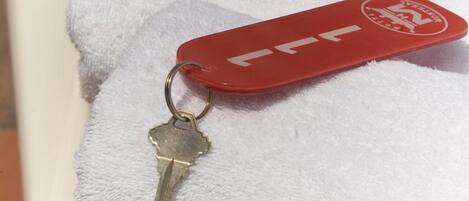 Un llavero con una etiqueta roja y una llave, sobre una toalla blanca.
