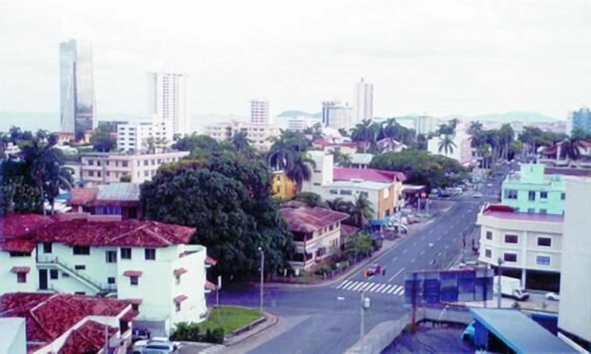 A cityscape with a variety of buildings, including a tall skyscraper, and a street with cars.