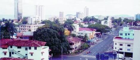 A cityscape with a variety of buildings, including a tall skyscraper, and a street with cars.