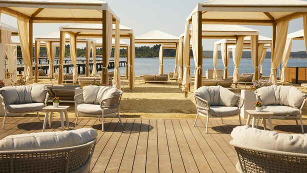A beachside lounge with wooden pergolas, wicker furniture, and a view of the water. - Hotel Palace Portoroz Operated by Minor Hotels (Piran)