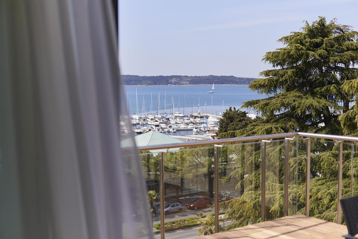 Ein Balkon mit Blick auf einen Yachthafen, Boote und eine entfernte Küste.