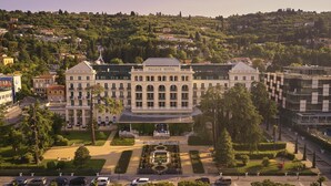 A large, historic building with a central courtyard, surrounded by modern buildings and a hilly backdrop. - Hotel Palace Portoroz Operated by Minor Hotels (Piran)