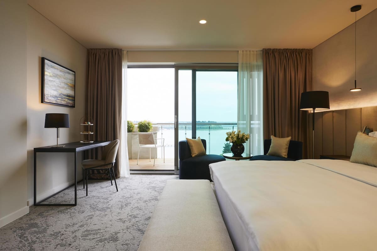 Ein Hotelzimmer mit Bett, Schreibtisch, Stuhl und Blick auf das Meer.