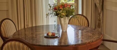 A round table with a vase of flowers, a plate with a pastry, and four chairs.