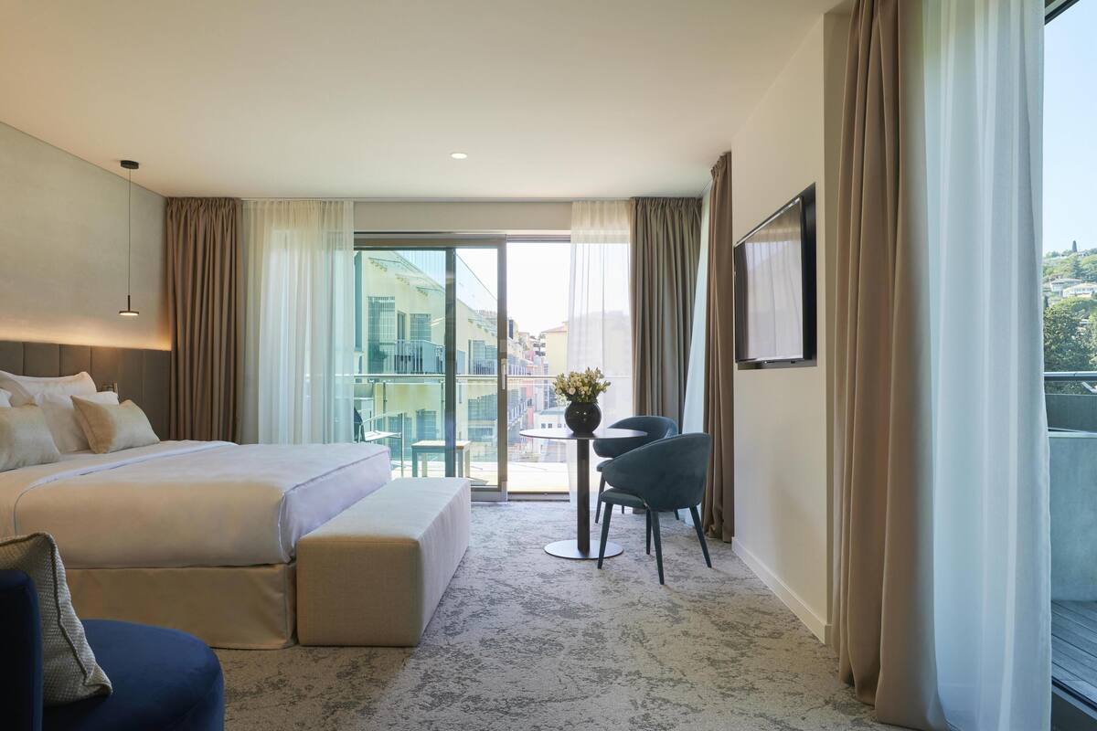Ein Hotelzimmer mit Bett, Sitzecke, Fernseher und einem Balkon mit Blick.