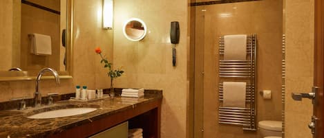 Un baño con lavamanos de mármol, un espejo, un teléfono, un perchero para toallas y una ducha.