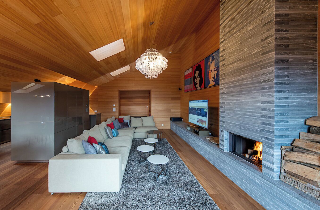 A modern living room with a fireplace, wooden ceiling, and a large TV.