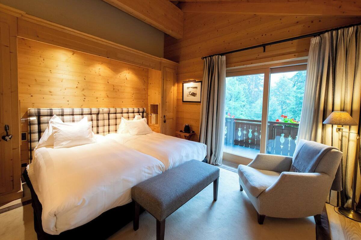 A wooden room with a large bed, a bench, and a chair.