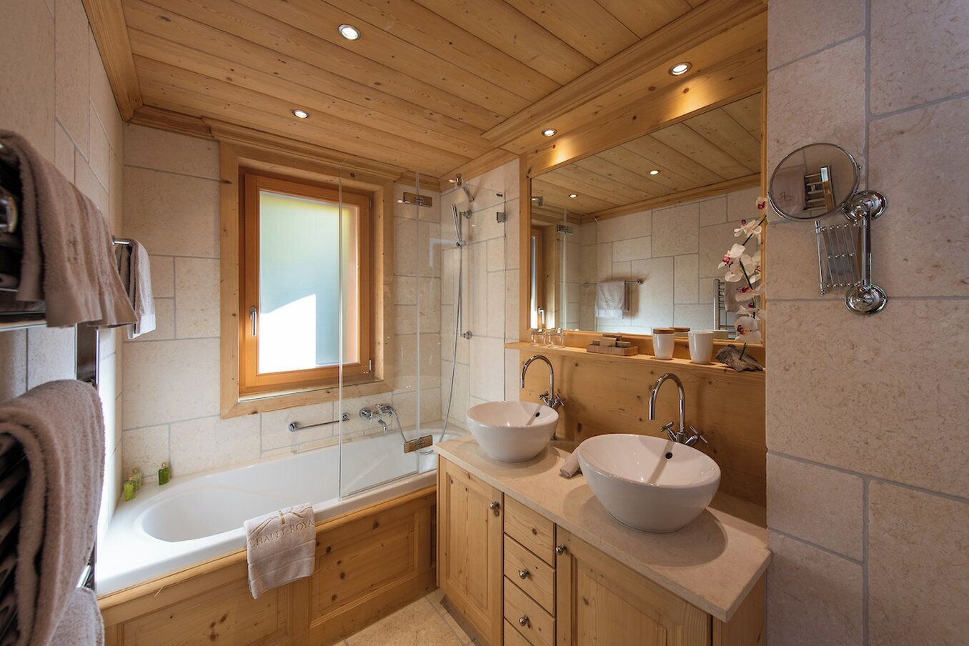 Ein modernes Badezimmer mit Badewanne, zwei Waschbecken, einer Dusche und einem großen Spiegel.