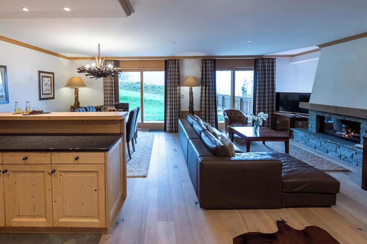 A modern kitchen with wooden cabinets, a dining area with a sofa and table, and a fireplace.