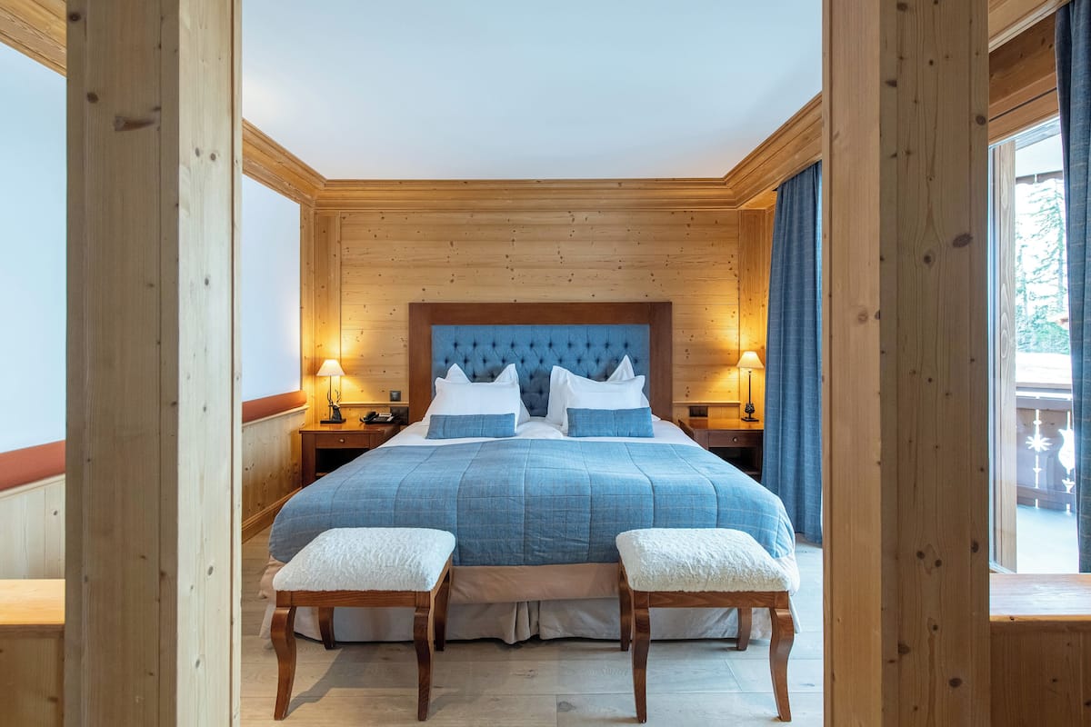 A bedroom with a large bed, wooden walls, and two bedside tables with lamps.