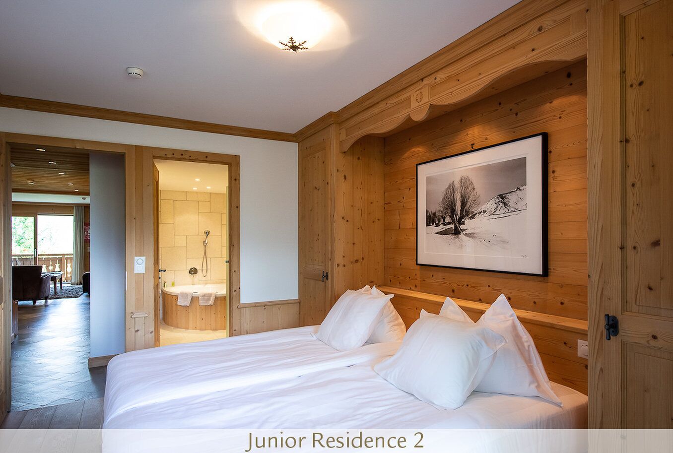Residencia Junior de dos habitaciones con cama, paneles de madera, un cuadro enmarcado y un baño con ducha.