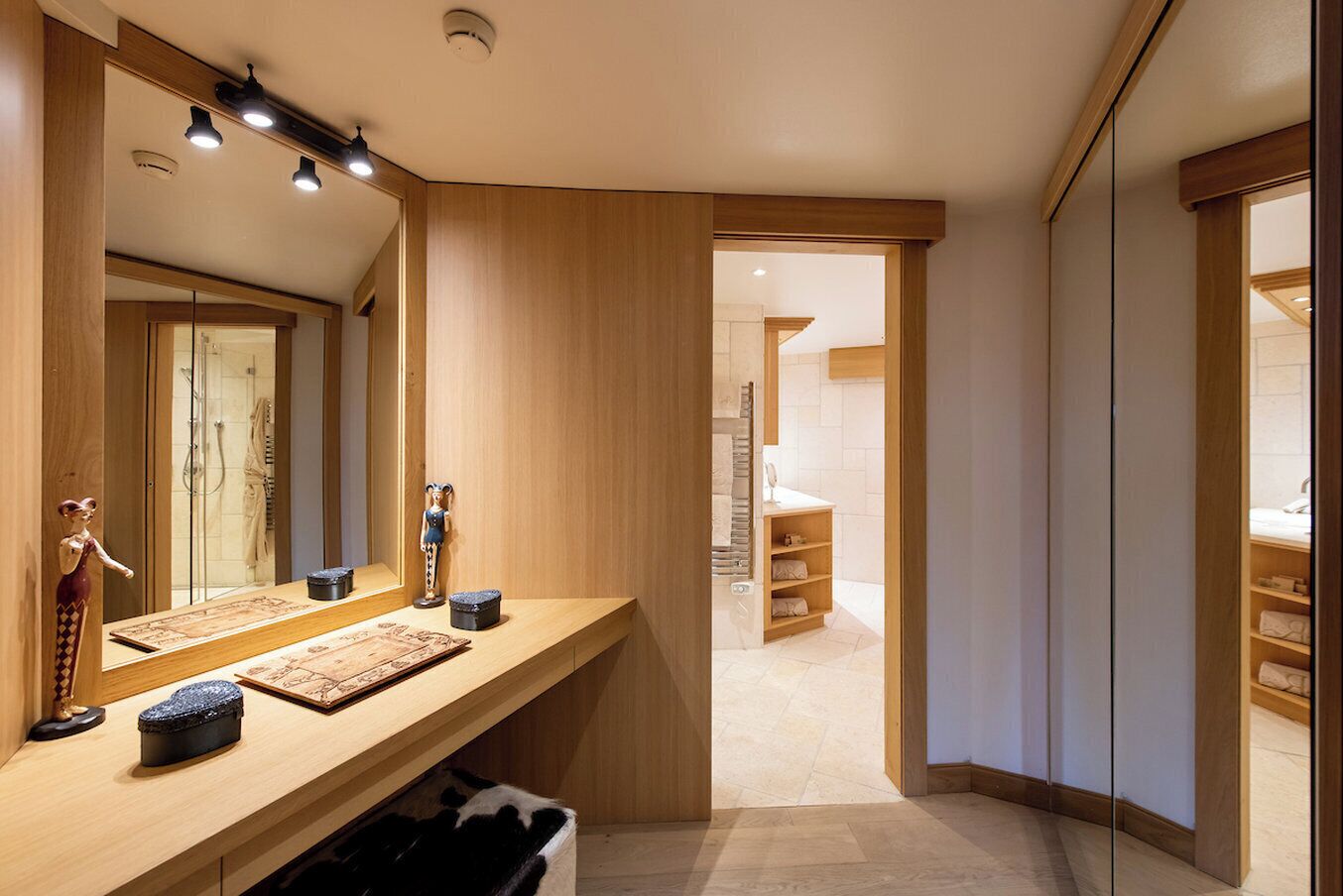 A modern bathroom with a wooden vanity, a large mirror, and a walk-in shower.