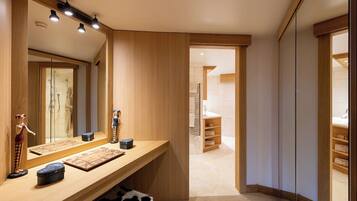 A modern bathroom with a wooden vanity, a large mirror, and a walk-in shower.