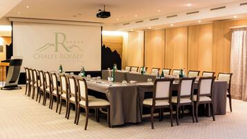 Ein Konferenzraum mit einem langen Tisch, Stühlen und einem Präsentationsbildschirm mit dem Logo 'Chalet Royal'.