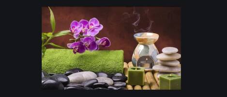 A spa setting with a purple orchid, green moss, black and white stones, and a stack of stones.