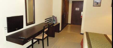 A hotel room with a bed, a desk with a chair, a television, and a mirror.