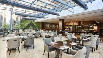 A spacious restaurant with high ceilings, exposed ductwork, and a modern interior design.