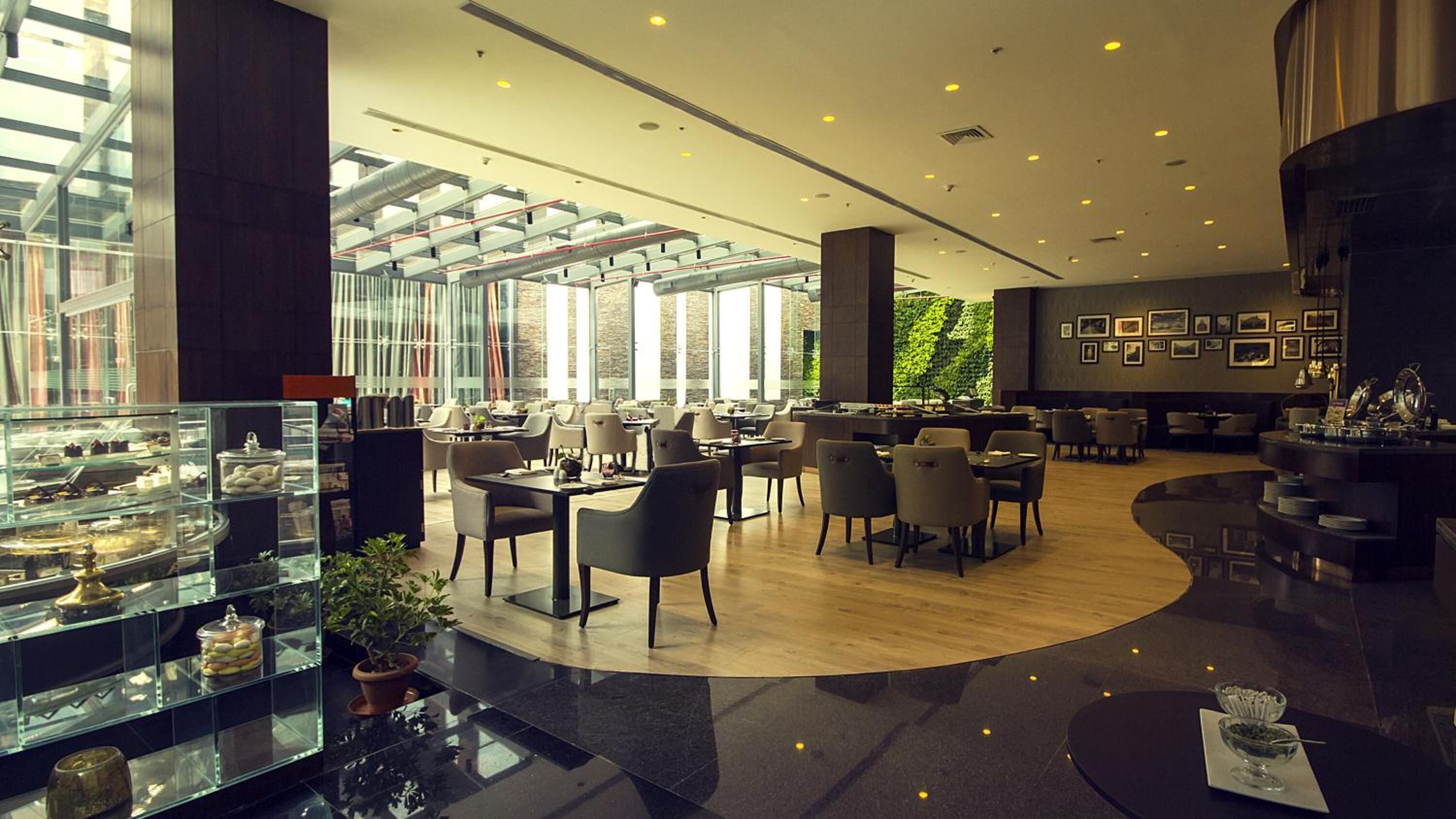 A modern hotel lobby with glass display cases, seating areas, and a wall with framed pictures.