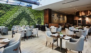 Un restaurante moderno con una pared verde, detalles de madera y diversas opciones de asientos.