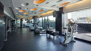 Un gimnasio moderno con equipo de ejercicio, ventanas amplias y un diseño de techo original.